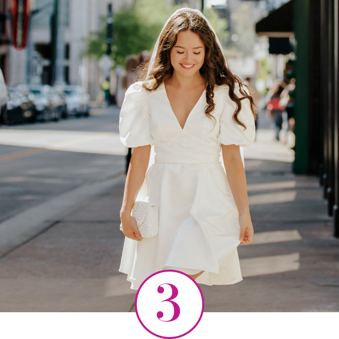 bride holding a handbag and walking down the sidewalk
